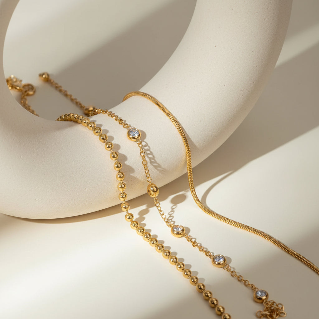 Gold beaded necklace with clear stones on a beige surface
