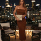 After Dark Strapless Midi Dress in brown ribbed fabric with side slit, paired with beige clutch on rooftop at night.