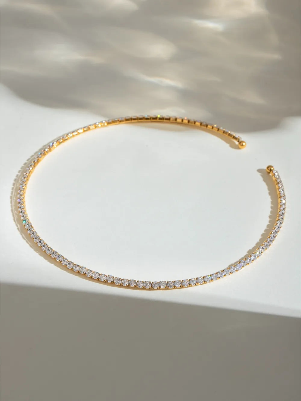Gold bracelet with clear stones on a light background