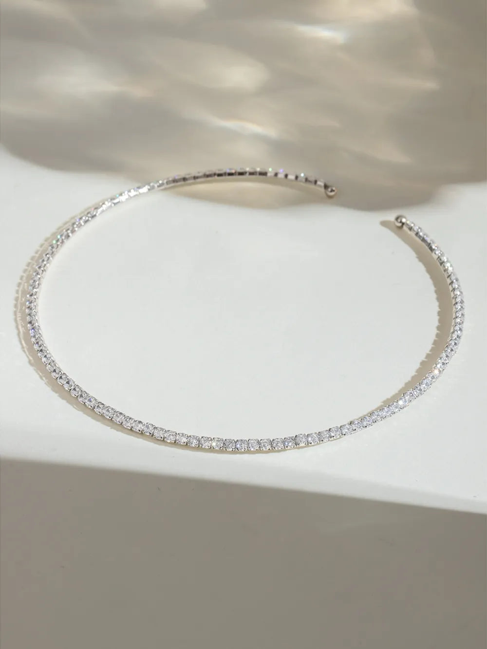 Silver hoop earring on a white surface with a soft background