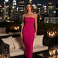 After Dark Strapless Midi Dress in fuchsia, ribbed stretch fabric with side slit, worn by a woman on rooftop at night